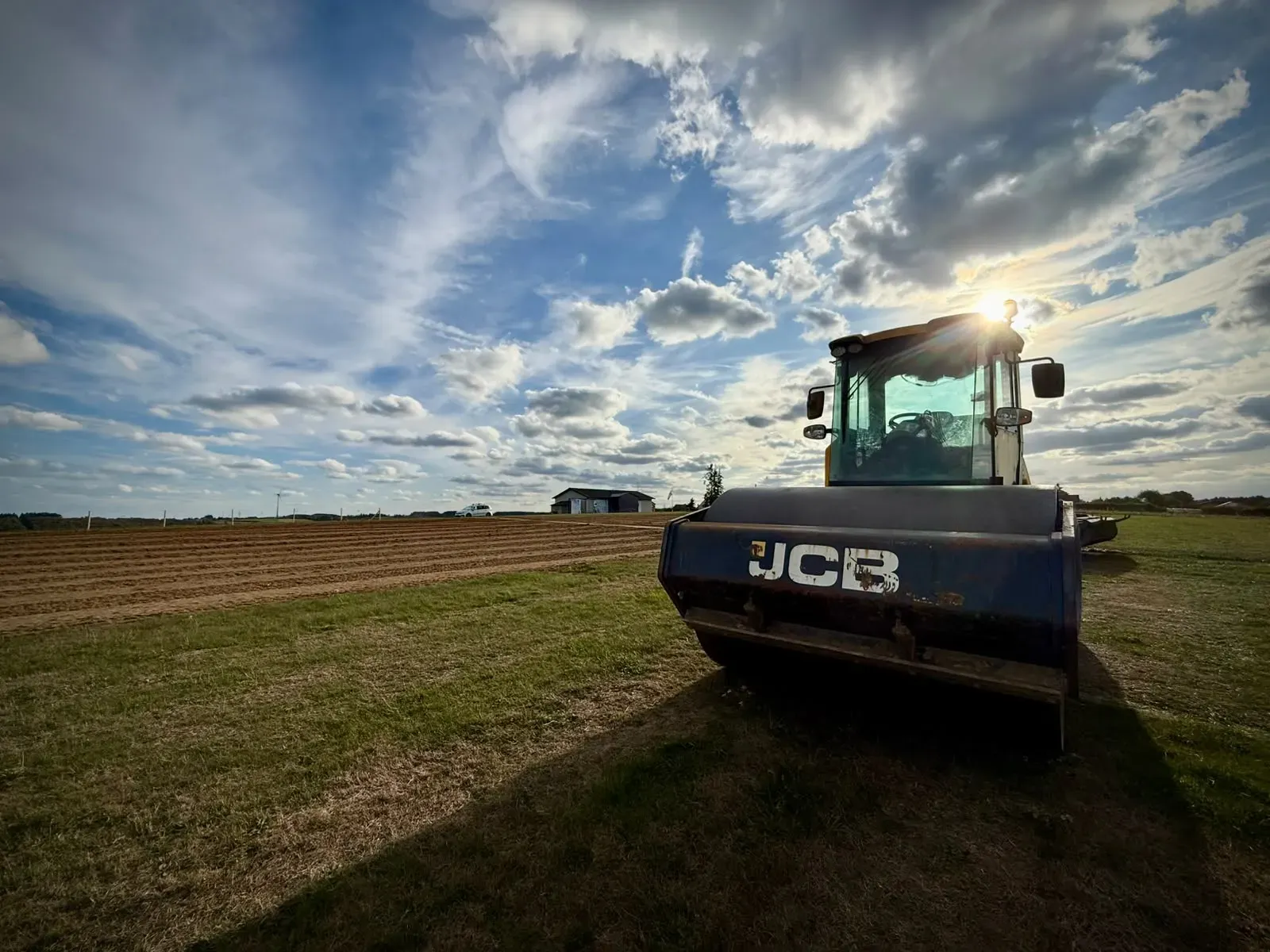 A single drum roller parked at the edge of the worked ground, the ploughed surface stretching away to the left