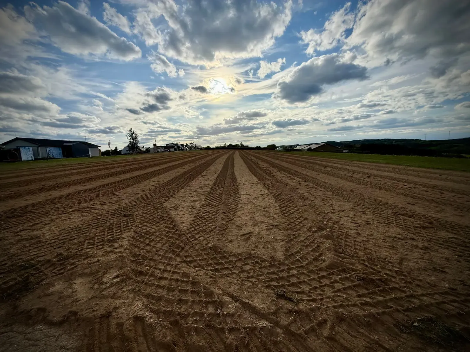 Roller tracks running the full width of the ploughed runway, with the hangars and the village on the horizon